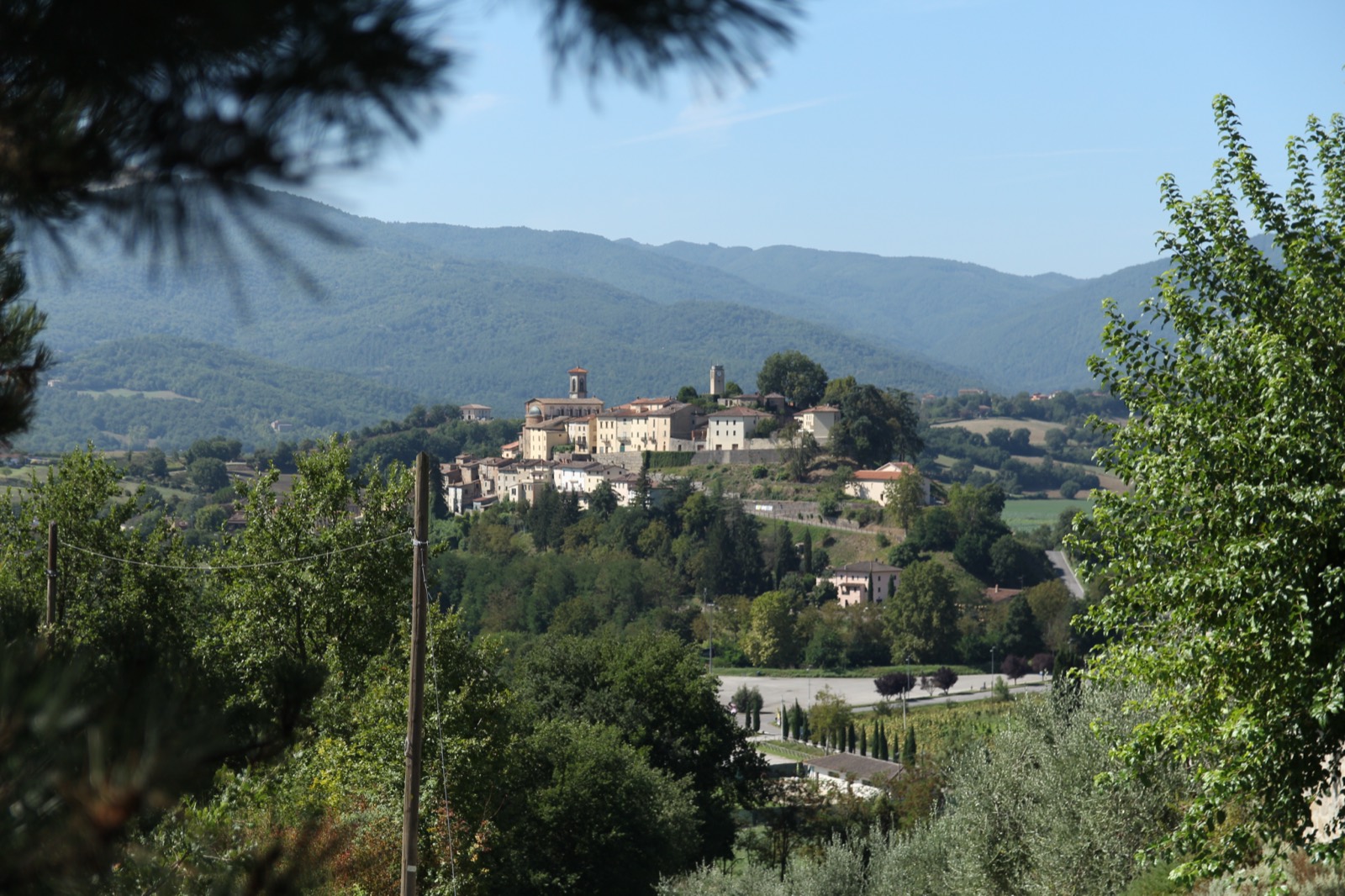 Un borgo in collina con case in pietra che si alzano sopra colline boscose